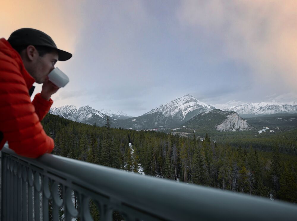 A person enjoys a coffee at the rimrock Resort Hotel in the early morning while looking at mountains.